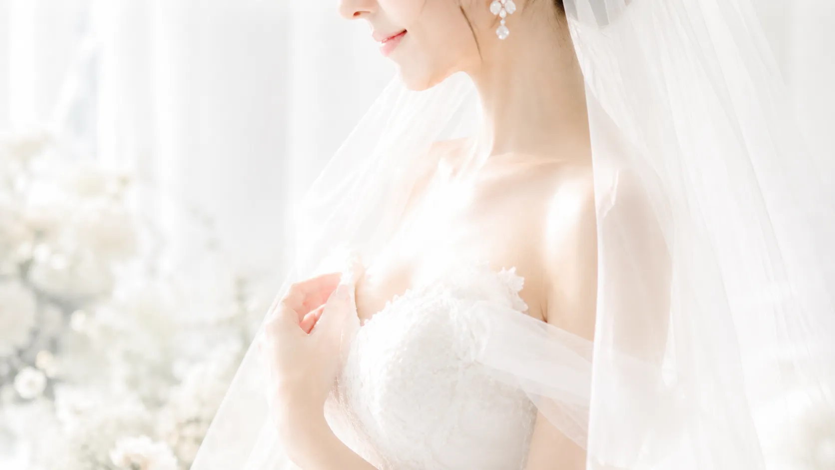ベールをまとった洋装の花嫁が白い光の中で横顔とデコルテを上品に見せているブライダルエステのイメージ写真